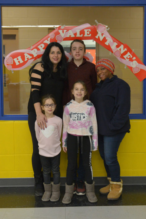 Mitzi Benvenuto poses with a family in front of the Valentine's decorated window.